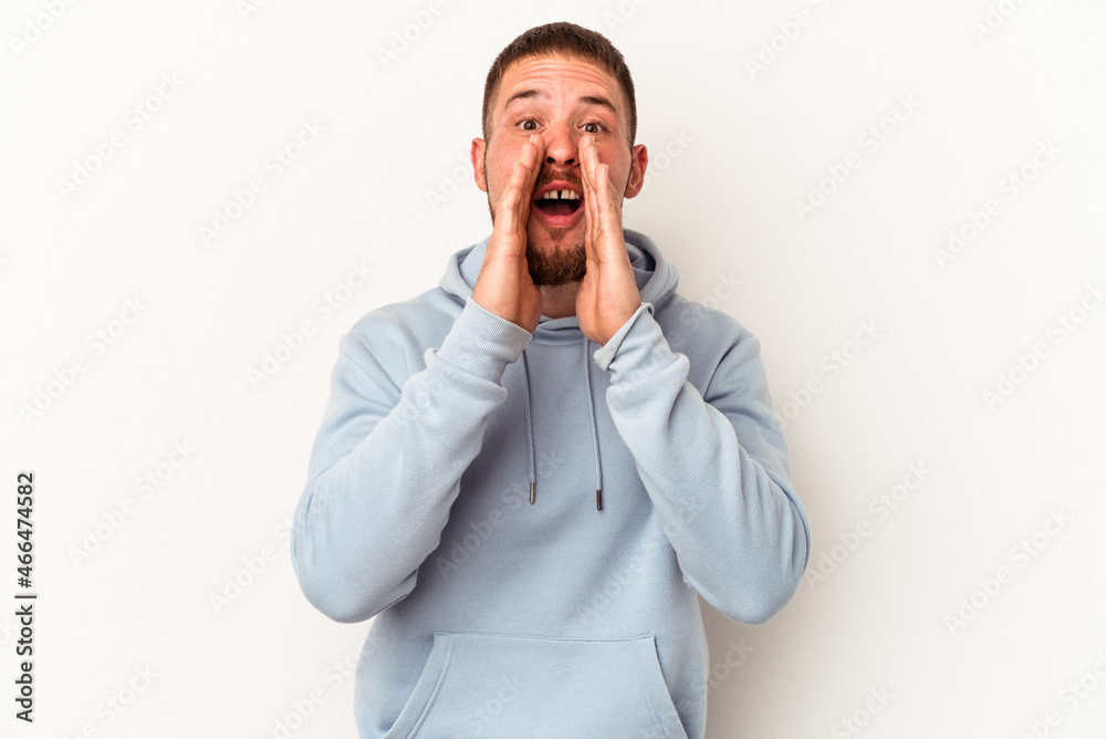 Young caucasian man with diastema isolated on white background saying a gossip, pointing to side reporting something.