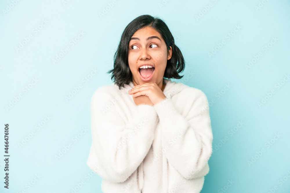 Young latin woman isolated on blue background praying for luck, amazed and opening mouth looking to front. Young latin woman isolated on blue background praying for luck, amazed and opening mouth looking to front.