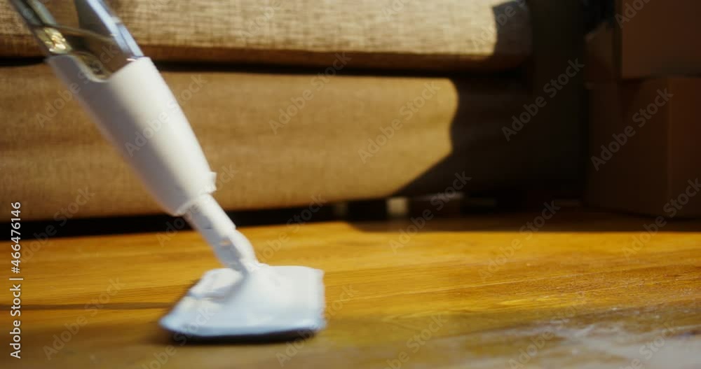 A woman washes the floor with a mop with a water sprinkler, close-up A woman washes the floor with a mop with a water sprinkler, close-up
