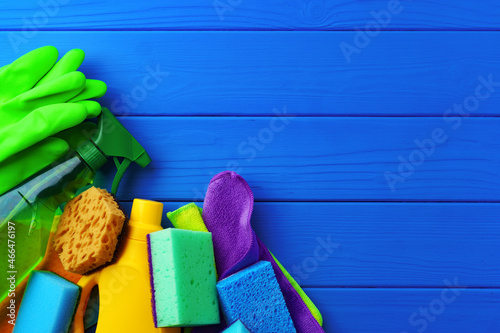 Household cleaning supplies on blue wooden background flat lay