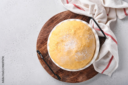 Raw yeast dough with pumpkin in white bowl covered with towel on the floured kitchen table, recipe idea. Concept home baking bread, buns or cinnabon or making dough.