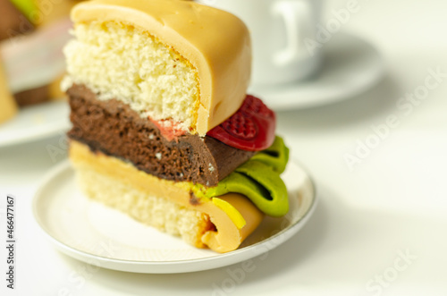 Piece of the Burger Cake, Madeira and chocolate sponge layered cake, filled with frosting covered with soft icing and edible sugar decorations