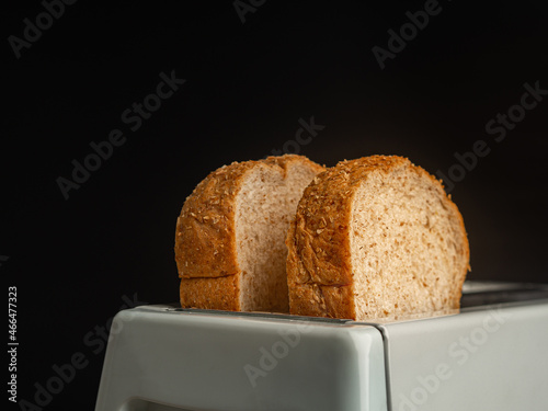 Rich and soft whole wheat bread in the toaster with a black background. Close-up photo. Space for text