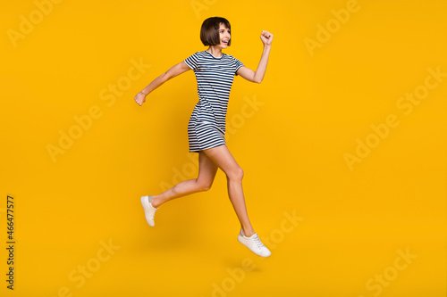 Full size photo of crazy brunette young lady run wear dress sneakers isolated on yellow background © deagreez