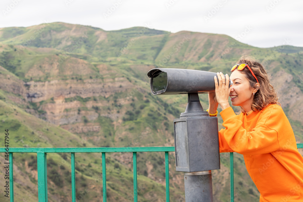 A woman on an observation deck in the mountains watching birds or distant views.