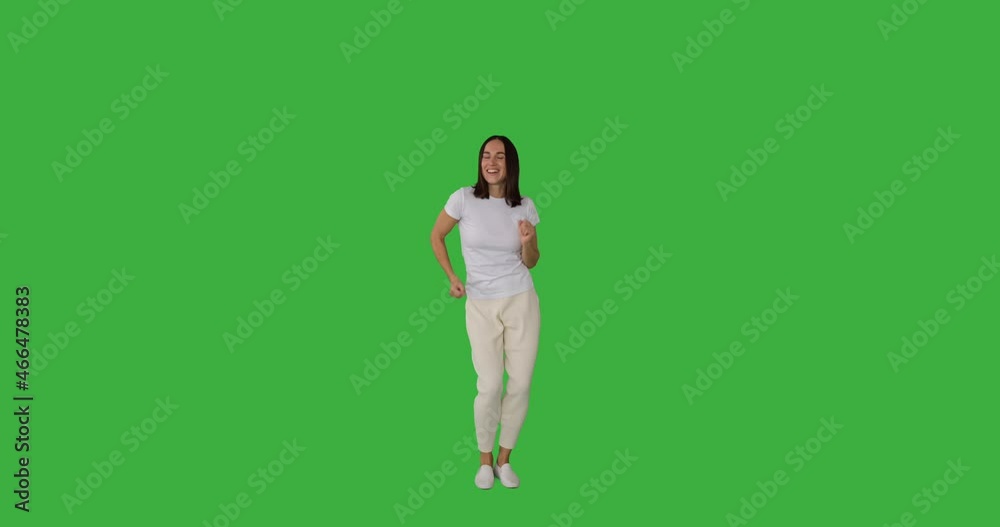 Carefree woman having fun dancing over green background