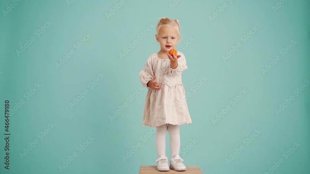 Concentrated girl throwing a small basketball in blue studio Concentrated girl throwing a small basketball in blue studio