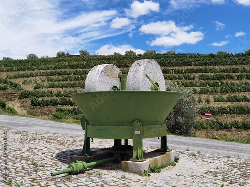 Monumento em estrada com uma máquina de moer a azeitona para a produção do azeite com uma vinha ao fundo photo