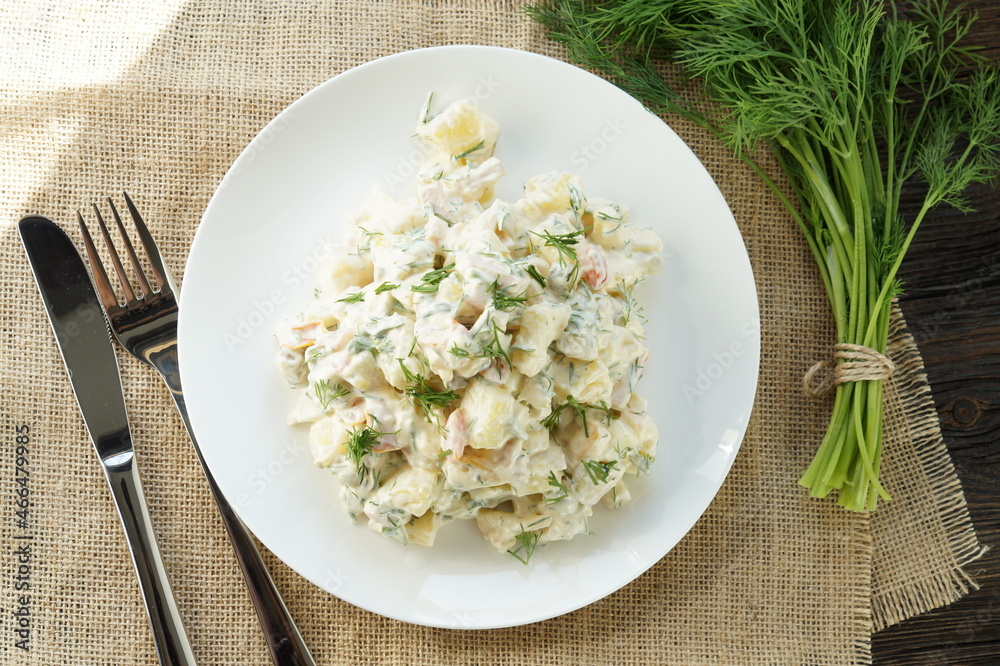 Traditional German potato salad with cucumber and mayonnaise. Top view. Potato salad with fresh radishes in a white bowl with dill and green onion on a rustic wooden table. Traditional German potato salad with cucumber and mayonnaise. Top view. Potato salad with fresh radishes in a white bowl with dill and green onion on a rustic wooden table.