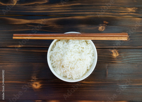 Bowl of cooked rice top view on wooden board.