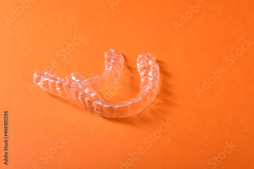 Plastic mouthguards for teeth, side view, on an orange background