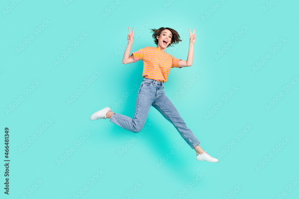 Photo of charming sweet young woman dressed striped t-shirt smiling jumping showing v-signs isolated teal color background