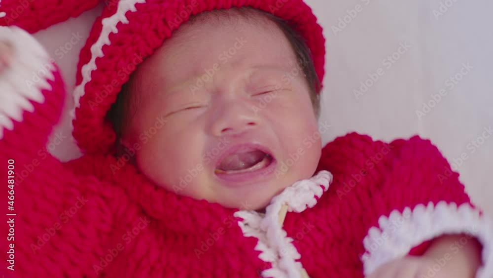 Cute Newborn baby wearing santa costume lying and crying waiting for celebrate merry christmas and happy new year.Calm of infant baby sleep with red santa cloth Cute Newborn baby wearing santa costume lying and crying waiting for celebrate merry christmas and happy new year.Calm of infant baby sleep with red santa cloth