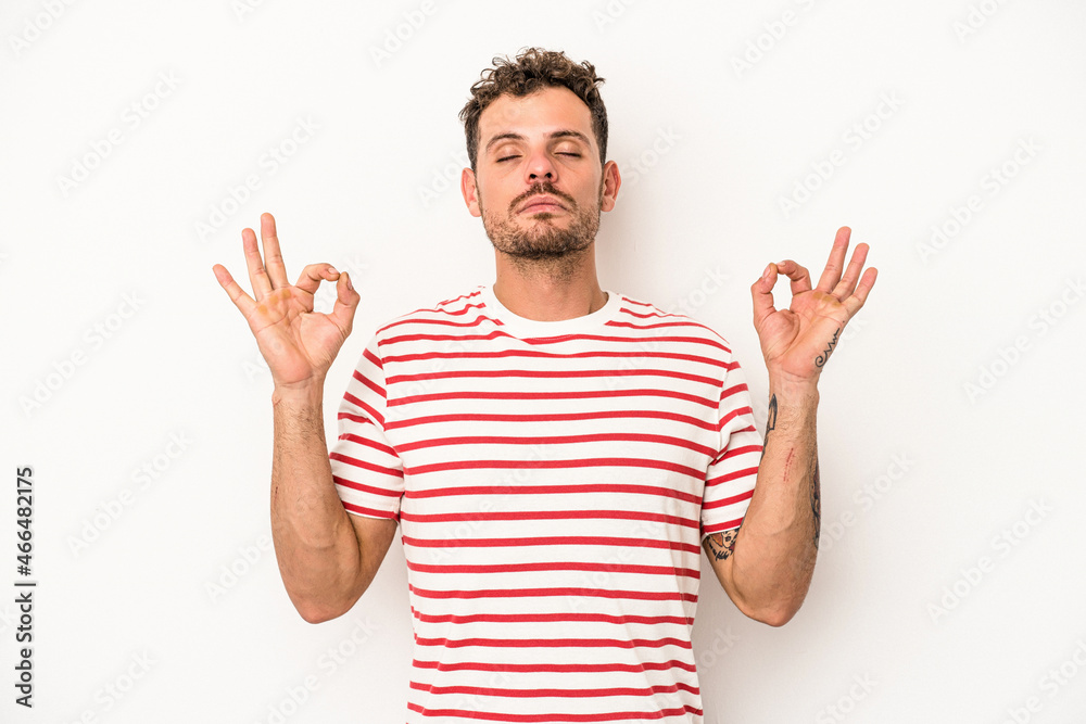 Young caucasian man isolated on white background relaxes after hard working day, she is performing yoga. Young caucasian man isolated on white background relaxes after hard working day, she is performing yoga.