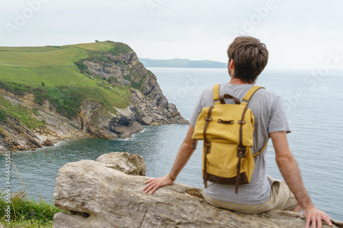 Fotografie Adventurous caucasian man isolated sit on a bench with selective focus on the cliff