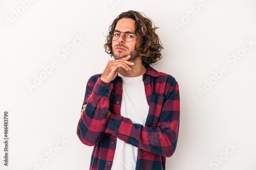 Young caucasian man isolated on white background suspicious, uncertain, examining you.