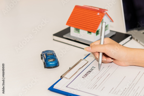 Toyhouse and car on the table Saving for the future manage to a successful business and finance concept Car and home models with agents discussing a buy-to-sale contract, insurance, or real estate loa photo