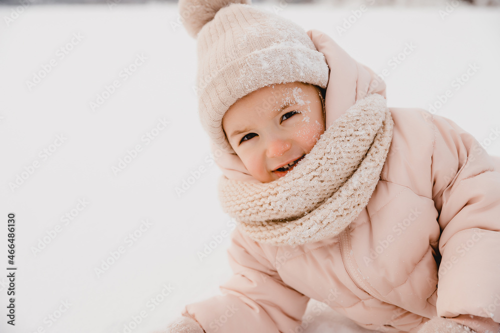 Winter cheerful little child playing throws up snow outdoors. The girl is lying in the snow, playing and having fun. Winter cheerful little child playing throws up snow outdoors. The girl is lying in the snow, playing and having fun.