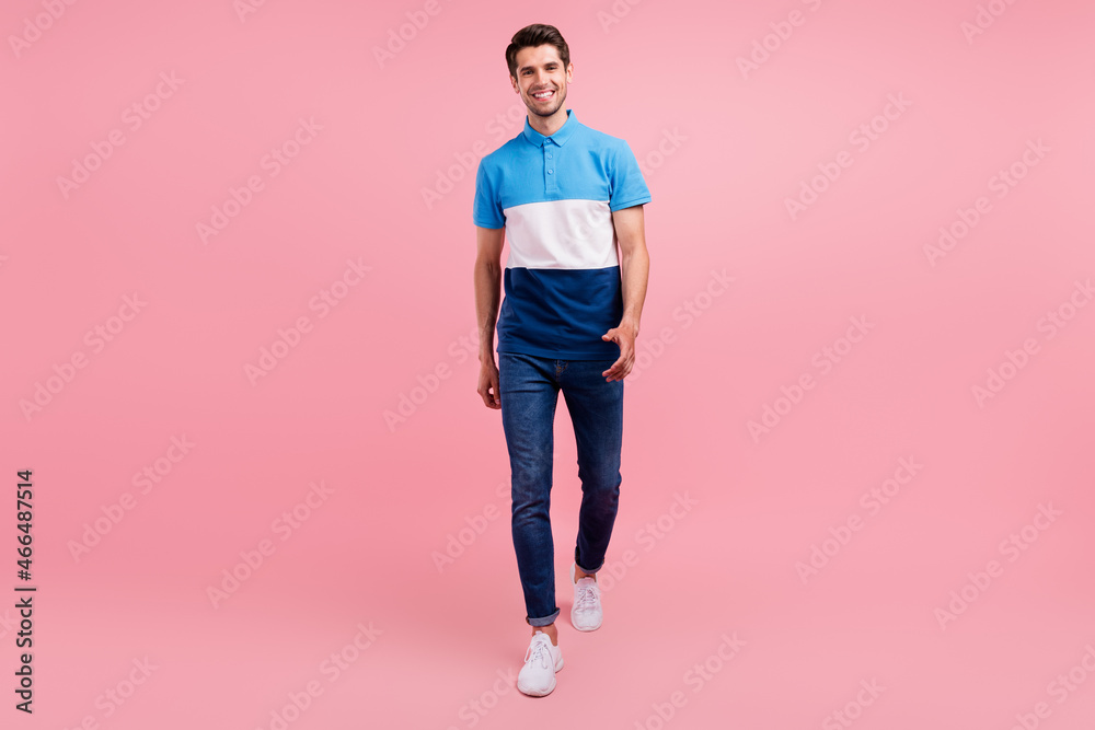 Full length photo of positive brunet millennial guy go wear polo jeans sneakers isolated on pink background Full length photo of positive brunet millennial guy go wear polo jeans sneakers isolated on pink background