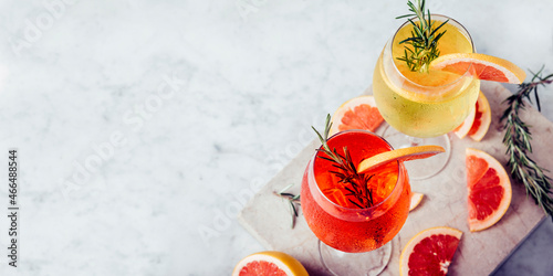 Tableau sur toile Red and white aperol spritz garnish in wine glasses with rosemary and grapefruit on luxury marble table