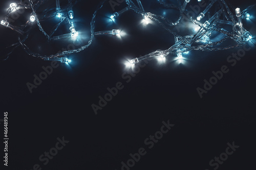 glowing christmas garland with cold light close up soft selective focus macro top view with place for text on dark background