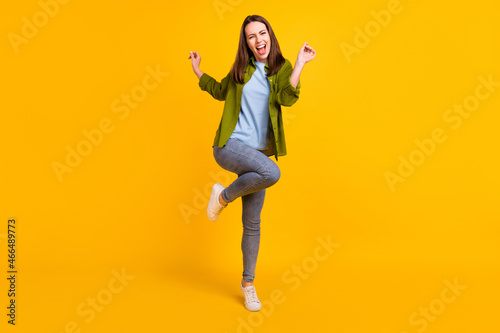 Photo of charming funky young lady wear green shirt smiling dancing isolated yellow color background