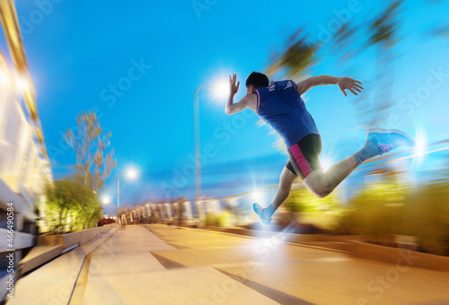 a man as athlete runner in high speed running action on the road toward the light with night sky background.