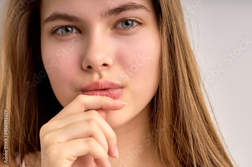 Adorable caucasian teenage girl face close-up photo, looking at camera thoughtfully, thinking about something, isolated on white background. copy space, portrait. human emotions, people lifestyle