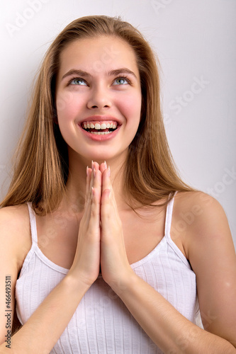 Young caucasian female keeping hands together  praying or begging  smiling happily  asking for something  looking up  excited with birthday celebration  getting gifts. isolated on white background
