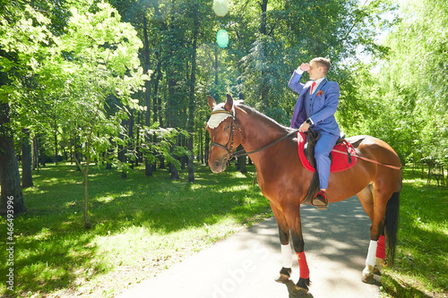 A man riding on horseback in green summer sunny park