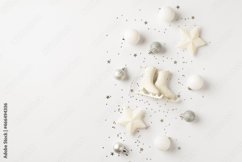 Top view photo of white and silver christmas tree decorations small ice skates balls stars and sequins on isolated white background with copyspace Top view photo of white and silver christmas tree decorations small ice skates balls stars and sequins on isolated white background with copyspace