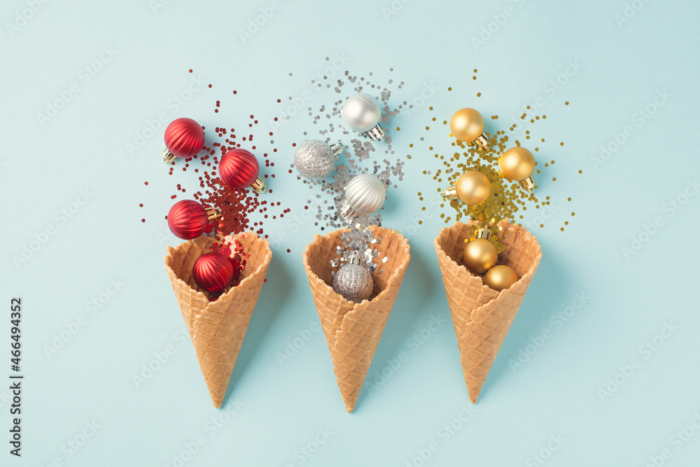 Top view photo of three ice cream cones with christmas decorations explosion of red silver and gold christmas tree balls and sequins on isolated pastel blue background Top view photo of three ice cream cones with christmas decorations explosion of red silver and gold christmas tree balls and sequins on isolated pastel blue background