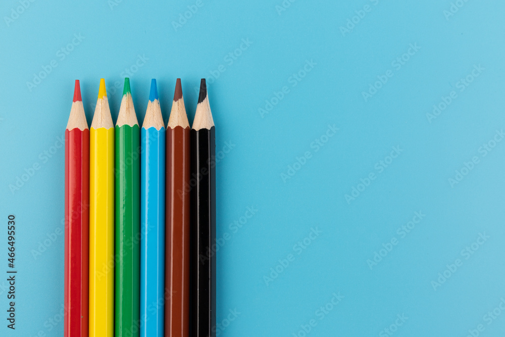 Six colored pencils close-up on a blue background with a copy of the space. The texture of bright colored wooden pencils. Six colored pencils close-up on a blue background with a copy of the space. The texture of bright colored wooden pencils.