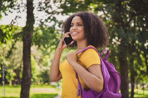 Profile side view portrait of attractive cheerful girl walking talking on phone carrying bag on fresh air outdoors
