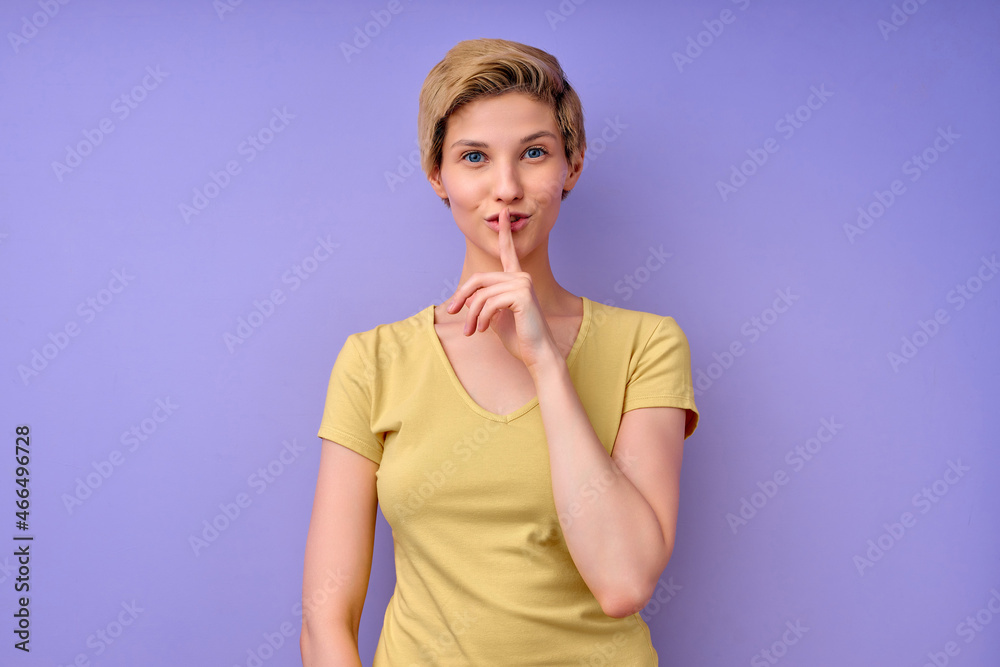 Beautiful caucasian woman keeping finger on mouth asking to be quiet, keep silence, looking at camera and smiling. tss... female posing isolated on purple background in studio, copy space. portrait Beautiful caucasian woman keeping finger on mouth asking to be quiet, keep silence, looking at camera and smiling. tss... female posing isolated on purple background in studio, copy space. portrait