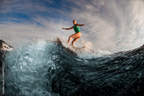 gorgeous view of woman wakesurfer riding down on the board on splashing wave. © fesenko