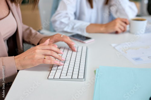 Business innovation and digital technologies.Young hardworking cropped businesswoman sitting in modern bright office and using computer. Corporate business concept  close-up female hands  copy space