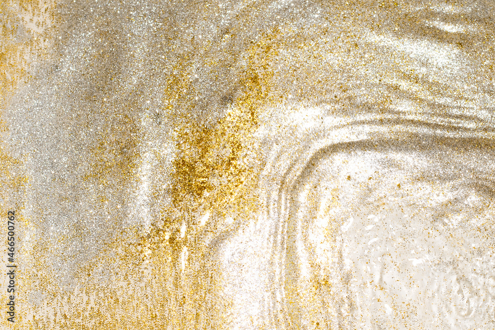 Golden and silver sparkles in water. Glitter and liquid texture. Abstract background with golden an silver particles. Shining celebration background. Festive backdrop for your projects.