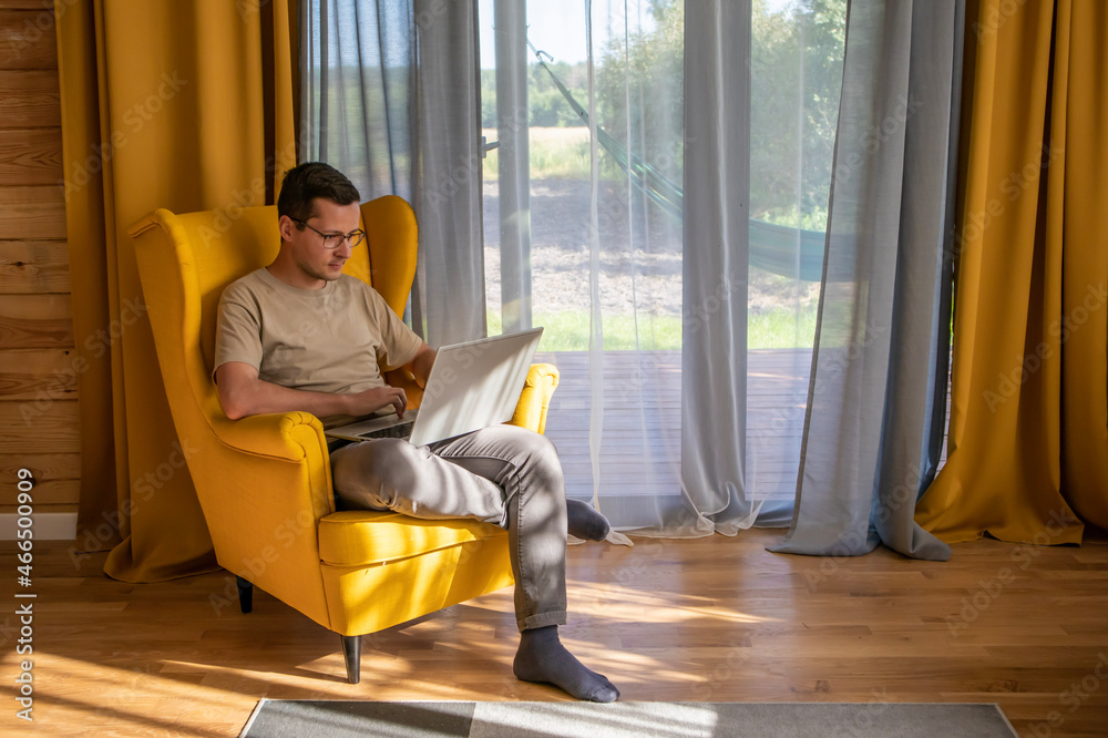 Comfortable place for working at home. A man is working in a big yellow armchair