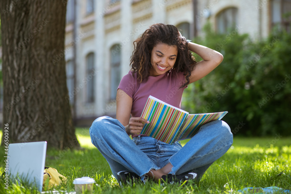 Obraz premium A pretty dark-skinned girl studying on the park