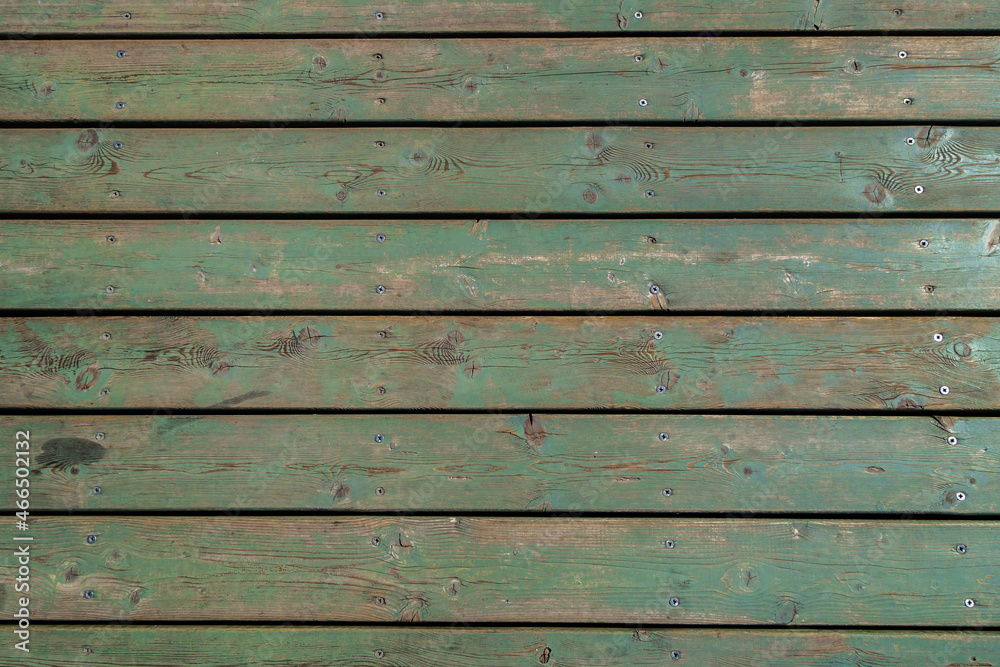 Obraz premium Wooden covering of the pedestrian street. The green color of the boards faded under the sun and weather. The boards are fixed with screws