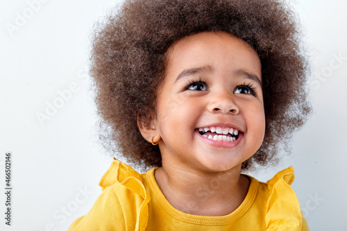 Foto close-up portrait of an adorable, awesome black african girl laughing smiling isolated on white studio background, look up and laugh