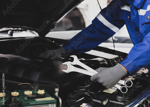 The mechanic works on the engine of the car in the garage, car repair service.