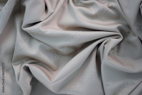 Draped canvas close-up. Abstract polyester fabric background. Top view of fabric with many folds. waves of satin material, shiny texture.