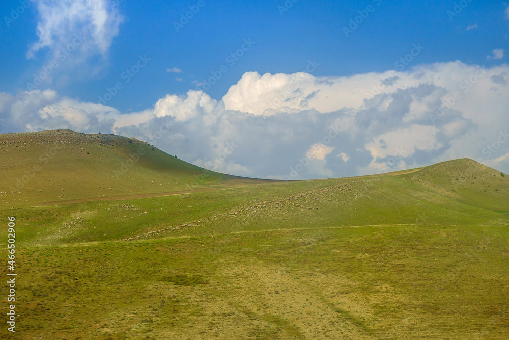 Scenic green hills, not yet burnt by the sun, against a blue cloudy sky. Shot in the Qashqadaryo region of Uzbekistan. Scenic green hills, not yet burnt by the sun, against a blue cloudy sky. Shot in the Qashqadaryo region of Uzbekistan.
