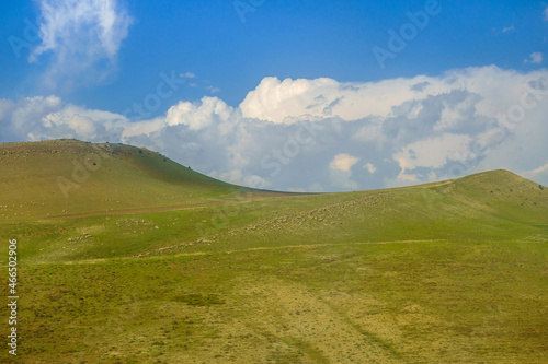Scenic green hills, not yet burnt by the sun, against a blue cloudy sky. Shot in the Qashqadaryo region of Uzbekistan.