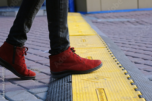 The girl in boots steps on the cable hose protector. Safety rubber cable protection cover for scene, outdoor events. A cable protection system protects electrical power cables against various factors