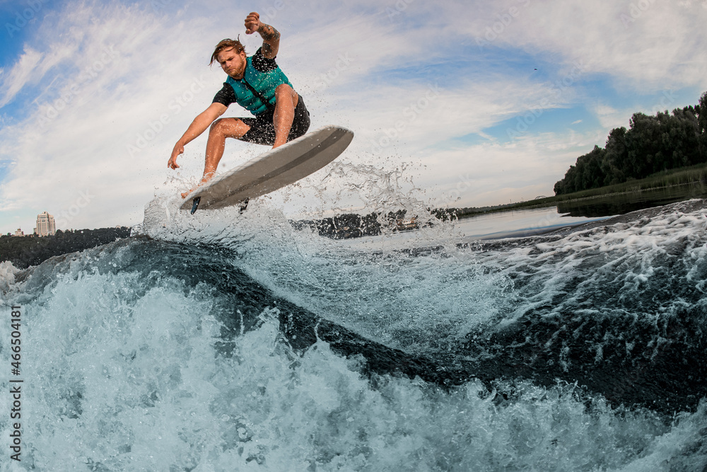 energy male wakeboarder performs tricks and jump over splashing river wave energy male wakeboarder performs tricks and jump over splashing river wave