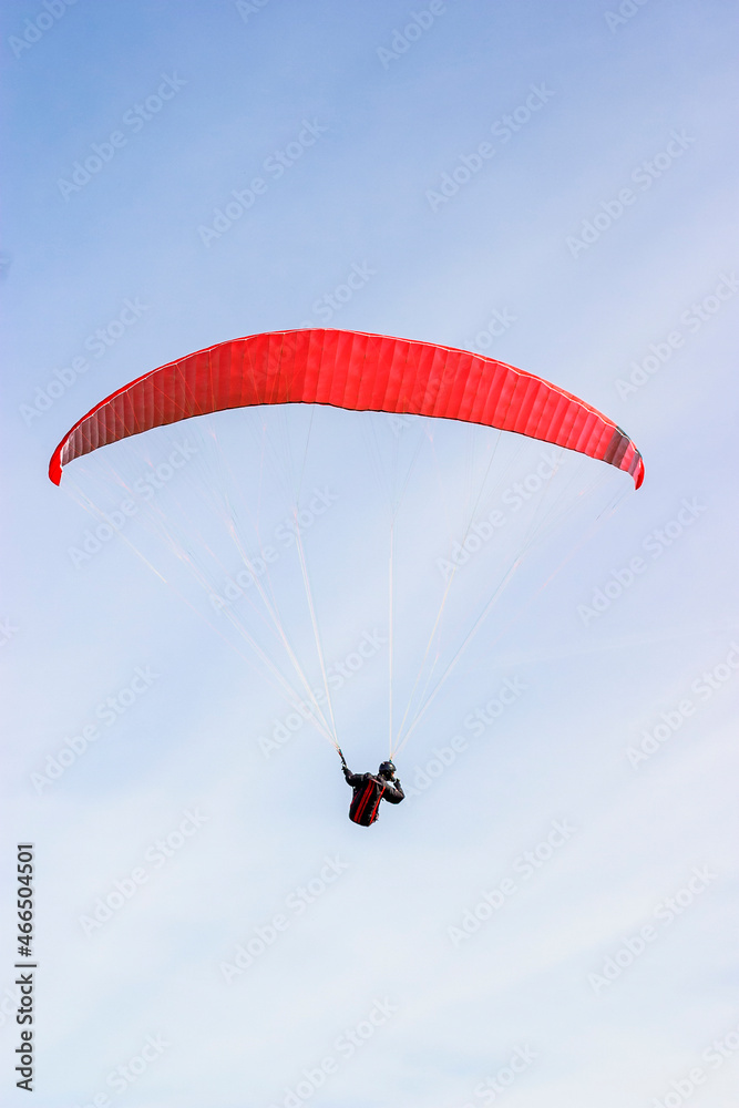 Paraglider flying with a red wing Paraglider flying with a red wing