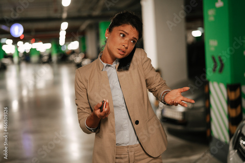 Businesswoman in suit unlocking car on parking. Beautiful woman talking to the phone.. photo